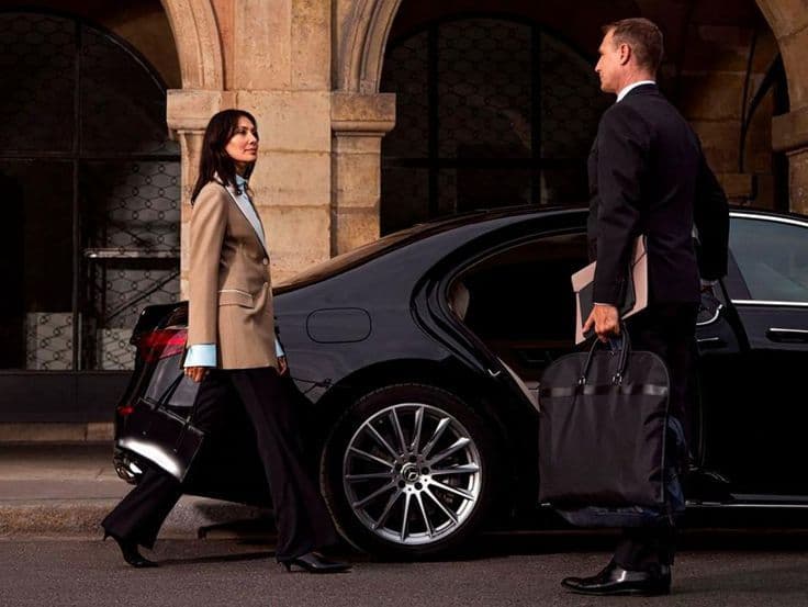 Chauffeur opening the door for a lady in a Mercedes-Benz on a Chelsea street in London
