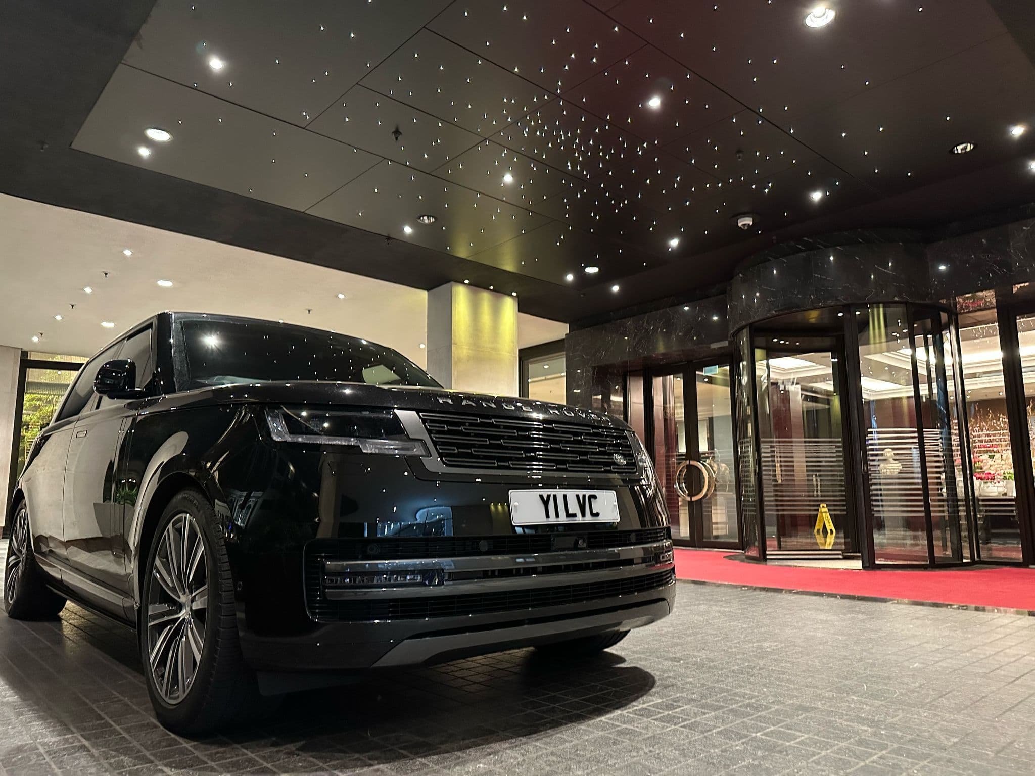 One of our fleet luxury SUVs parked in front of a five-star hotel, ready for VIP clients.