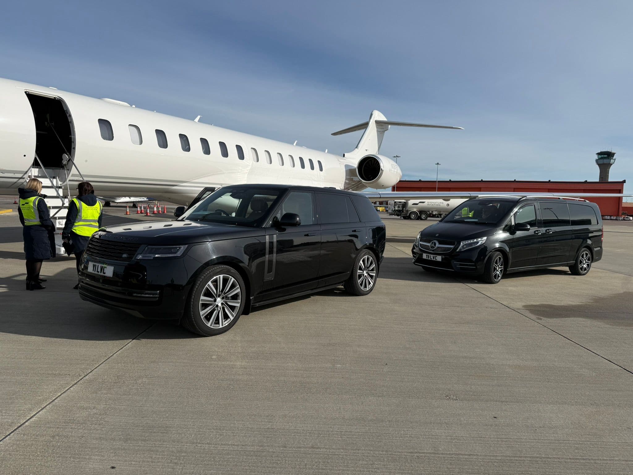 Luxury SUV and Mercedes-Benz V-Class chauffeur vehicles waiting beside a private jet for VIP guests in London.