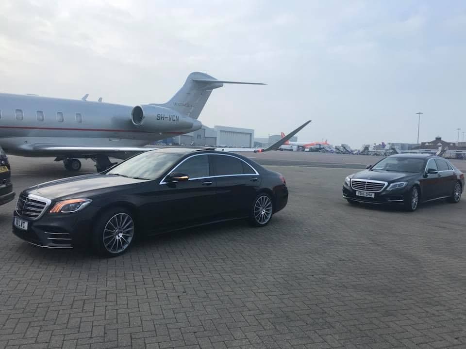 Two Mercedes-Benz S-Class luxury cars parked near a private jet at Harrods Aviation, waiting to collect VIP clients