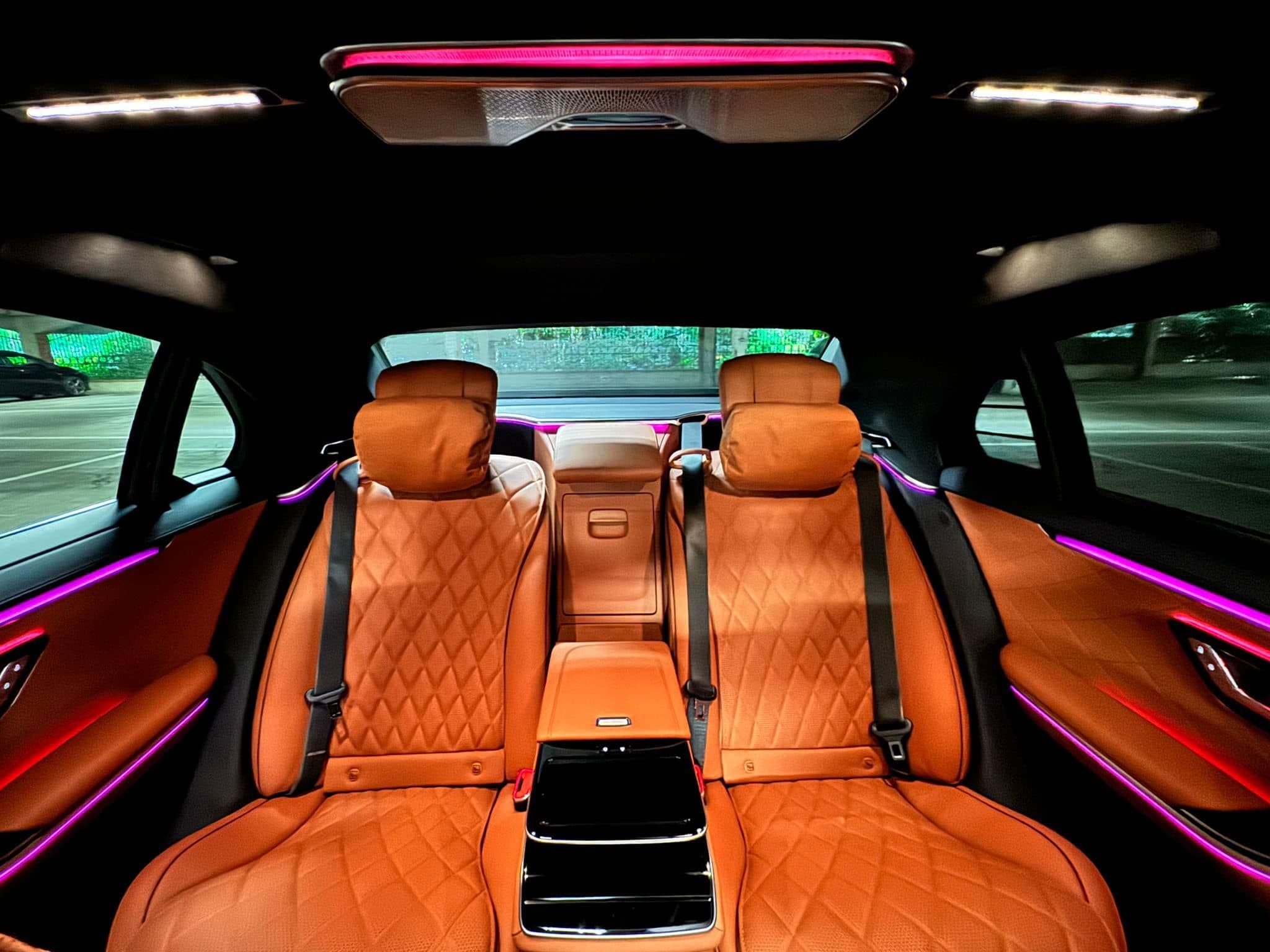 Interior of a Mercedes-Benz S-Class luxury sedan for VIP concert transfers, showing plush leather seats, ambient lighting, and spacious legroom for an elegant travel experience.