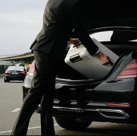 Chauffeur loading luggage into a Mercedes-Benz S-Class at Portsmouth Cruise Terminal for a transfer to Heathrow Airport