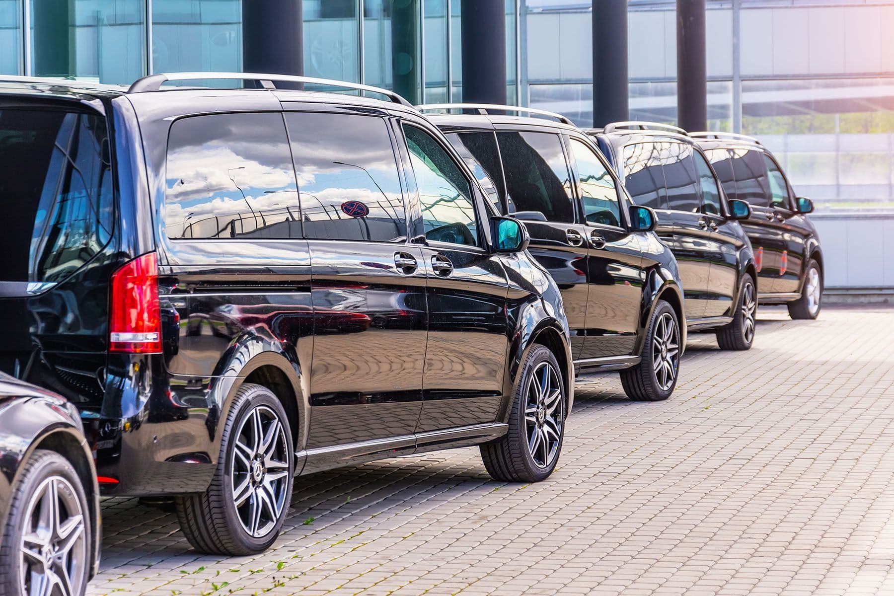 Group of Mercedes-Benz V-Class chauffeur vans outside a luxury hotel ready for cruise terminal transfers