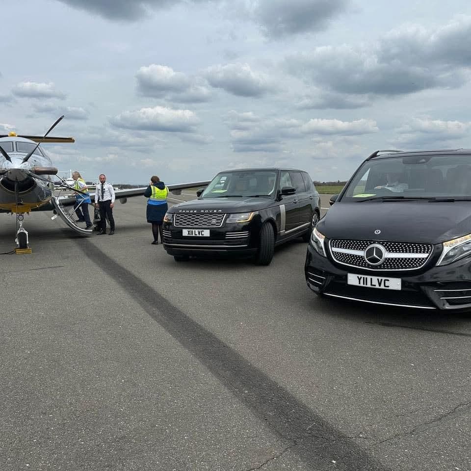 Luxury SUV and Mercedes V-Class chauffeur vehicles picking up client near private jet for a London sightseeing tour