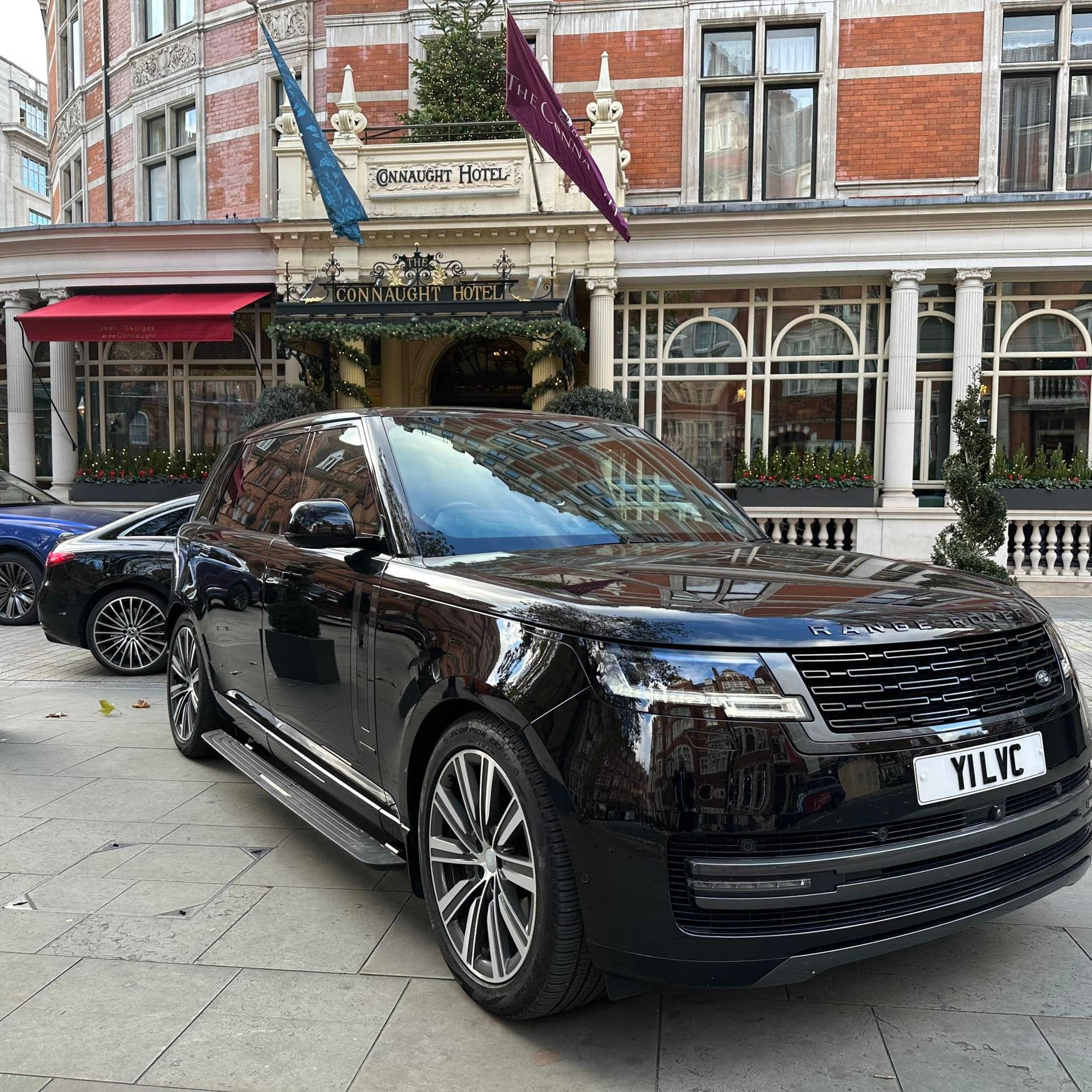 Luxury SUV parked in front of a hotel in Mayfair, London, with a professional chauffeur ready to collect a VIP client for transfer to Wembley Arena.