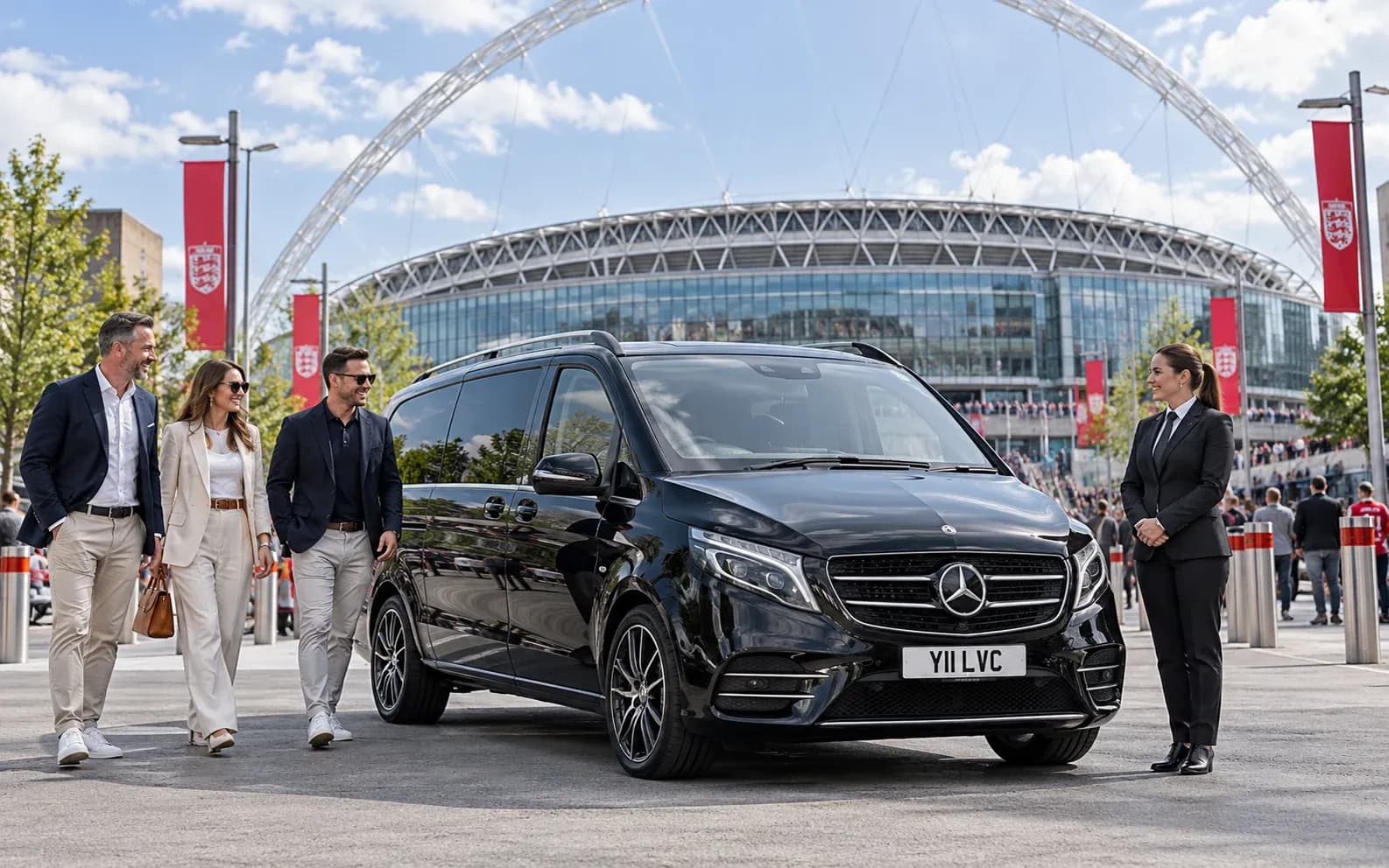 Female chauffeur greeting guests beside a Mercedes-Benz V-Class near Wembley Stadium.